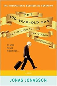 Yellow cover of an old man hunched out and pulling a suitcase behind him.